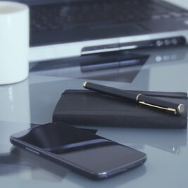 Szklany stół i telefon z kalendarzem i długopisem