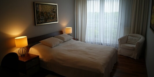 Łóżko posłane białą pościelą w apartamencie